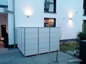 Ein modernes Außenmodul, befestigt an einer Hauswand, wahrscheinlich zum Verstauen von Gartenutensilien.