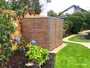 Ein Holzschuppen in einem Garten mit Pflanzen, geschwungenem Weg und blauer Dekoration.